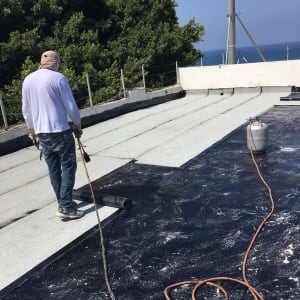 אדם מבצע איטום גג עם יריעות ביטומניות