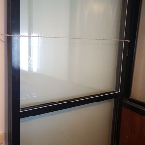 חלון זכוכית עם מסגרת שחורה וחבל מתוח