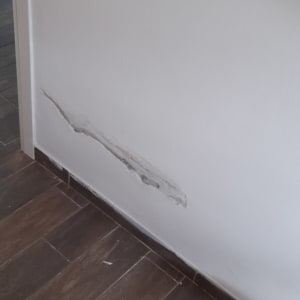 קיר עם סדק ודלי צבע על הרצפה