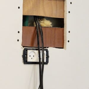 חורים בקיר גבס עם חוטי חשמל ותקע חשוף