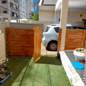 שער עץ פתוח בגינה עם דשא סינתטי וצעצועים