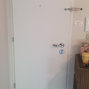 דלת לבנה עם ידית מתכת ובריח עליון