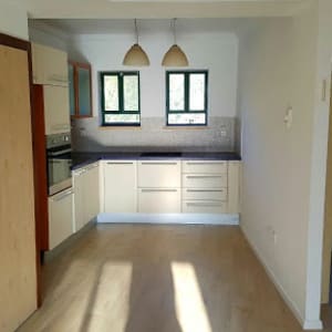 רצפת פרקט עץ בהירה בחדר עם מטבח קטן