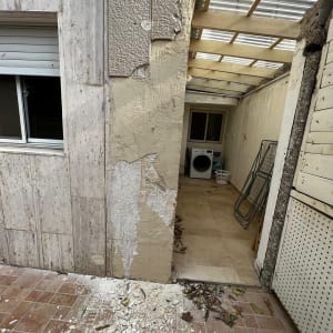 קיר מתקלף עם טיח מתפורר על הרצפה