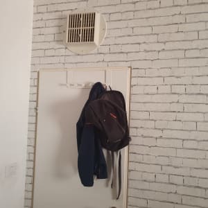 קיר עם טפט לבנים לבנות ופתח אוורור עגול