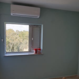 קיר חדר צבוע בגוון מרווה עם חלון ומזגן עילי