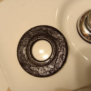 אטם גומי שחור על כיור לבן ליד ברז כרום