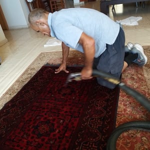 אדם מנקה שטיח עם שואב אבק