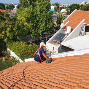 אדם עובד על גג רעפים עם כלי עבודה חשמלי