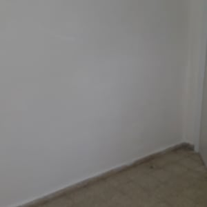 A plain white wall with a tiled floor.