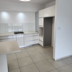 מטבח נקי עם רצפה מבריקה ומשטחי עבודה מסודרים