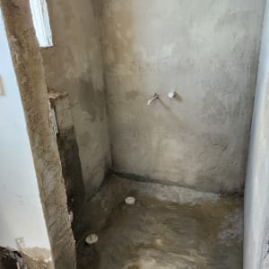 קירות בטון חשופים עם צינורות בולטים בשיפוץ חדר אמבטיה