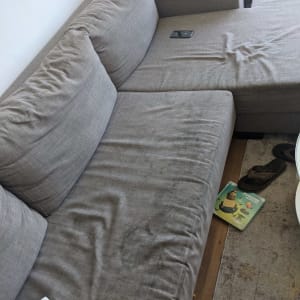 ספה אפורה עם כתמים וקמטים על הריפוד