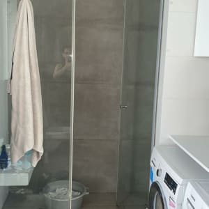 מקלחת עם מגבת תלויה ודלי על הרצפה