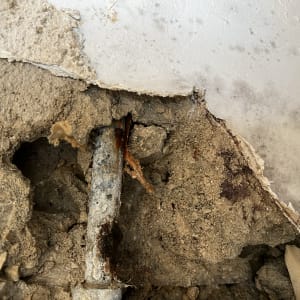 צינור חלוד בקיר עם טיח מתקלף