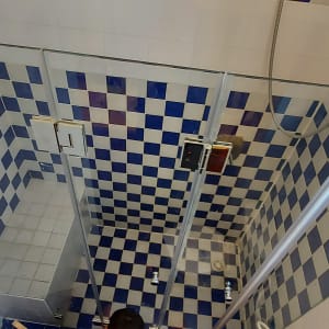 מקלחת עם אריחים כחולים ולבנים ודלת זכוכית