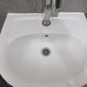 כיור לבן עם ברז מתכת, צינור מתחת