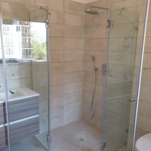 מקלחון זכוכית עם ראש מקלחת עגול וקירות אריחים