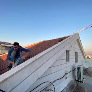 אדם עובד על גג רעפים עם צינור ביד