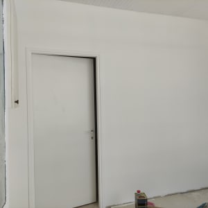 קיר צבוע בלבן עם דלת סגורה, כלי עבודה על הרצפה