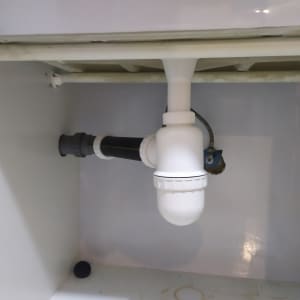 צנרת פלסטיק לבנה מתחת לכיור במטבח