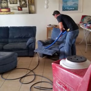 אדם מנקה ספה עם מכונת ניקוי ואקום