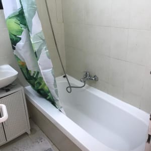 אמבטיה עם וילון ירוק, ברז ומקלחת יד