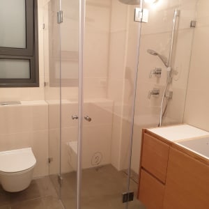 מקלחון זכוכית עם ראש מקלחת וכיור עץ