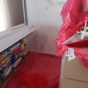 קיר צבוע חלקית עם כיסוי ניילון אדום על הרצפה