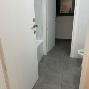 רצפת אריחים נקייה בחדר אמבטיה עם דלתות פתוחות