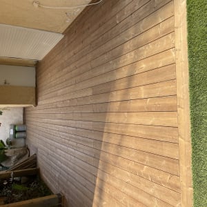 דק עץ ליד דשא סינתטי וצמחים