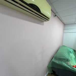 קיר צבוע בצבע ורוד בהיר עם ספה מכוסה בניילון ירוק