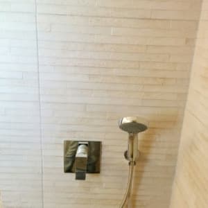 ברז מקלחת וכפתור על קיר אריחים לבנים