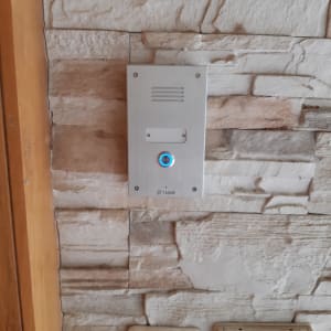 אינטרקום מותקן על קיר אבן עם כפתור מואר