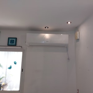 מזגן מותקן על קיר לבן עם תאורה מעל