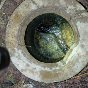 פתח ביוב עם מים עומדים ואבנים מסביב