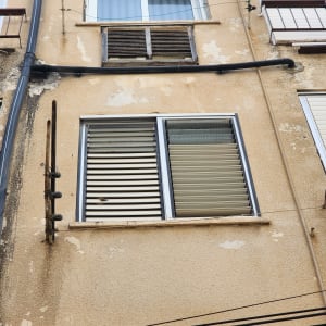 קיר חיצוני עם חלונות ותריסים, צינור מים על הקיר