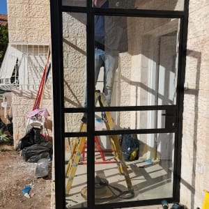 אדם מתקין מסגרת אלומיניום לדלת זכוכית