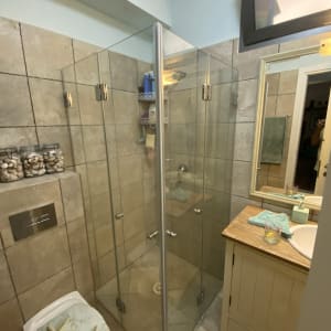 מקלחון זכוכית עם בקבוקי שמפו ומדף