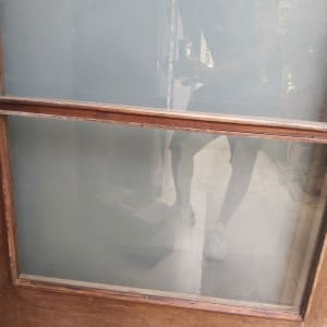 זכוכית מט עם השתקפות אדם ודלת עץ