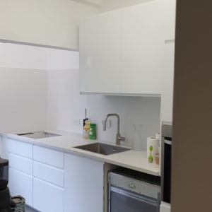 מטבח עם ארונות לבנים, כיור וברז מותקנים