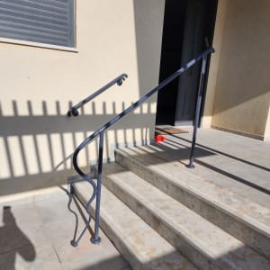 מעקה מתכת שחור על מדרגות אבן חיצוניות