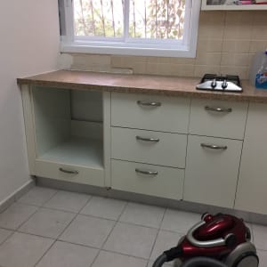 מטבח עם ארונות לבנים, כיריים ושואב אבק