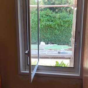 חלון אלומיניום פתוח עם מסגרת לבנה