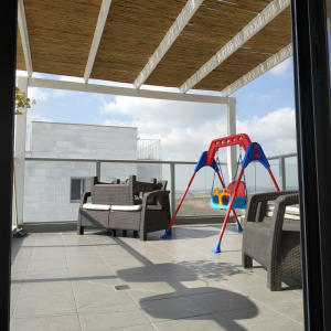 פרגולה מעץ מעל מרפסת עם ריהוט גן