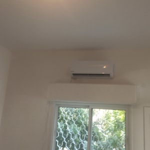 מזגן מותקן על קיר מעל חלון זכוכית