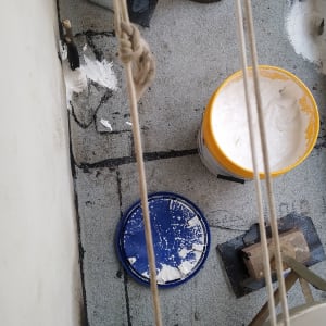 דלי עם חומר איטום לבן על רצפה אפורה