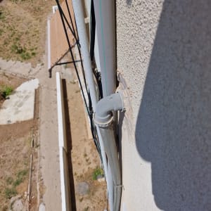 צינור פלסטיק אפור מחובר לקיר חיצוני