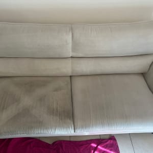 ספה עם כתמים כהים על המושב, מגבת ורודה על הרצפה