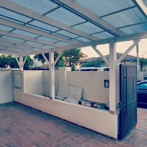 חצר עם פרגולה מעץ, דלתות פתוחות, קיר נמוך